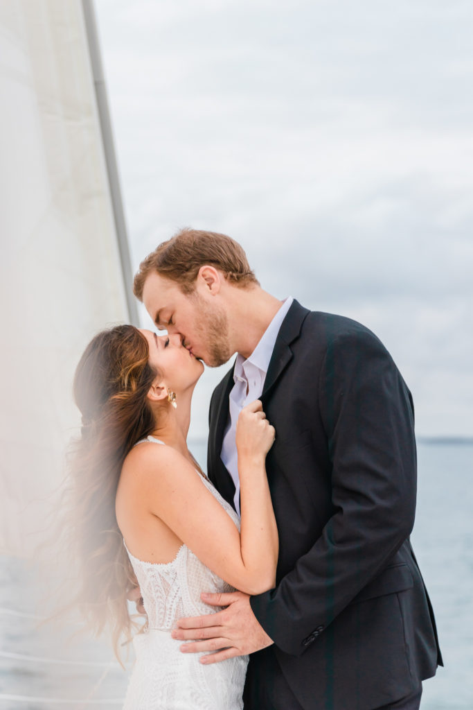 bride and groom kissing while eloping on a sailboat in charleston, sc
